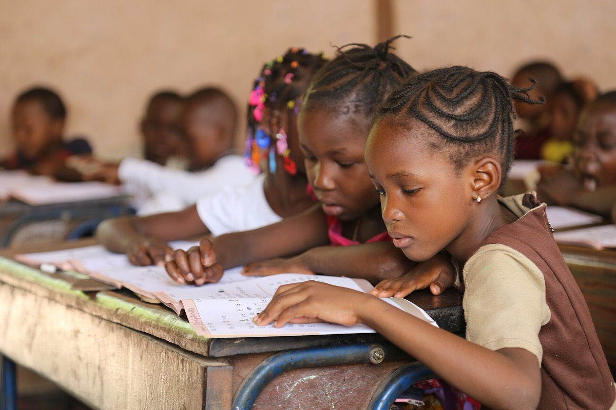 Girls reading their books together at a school desk in Bamako, Mali